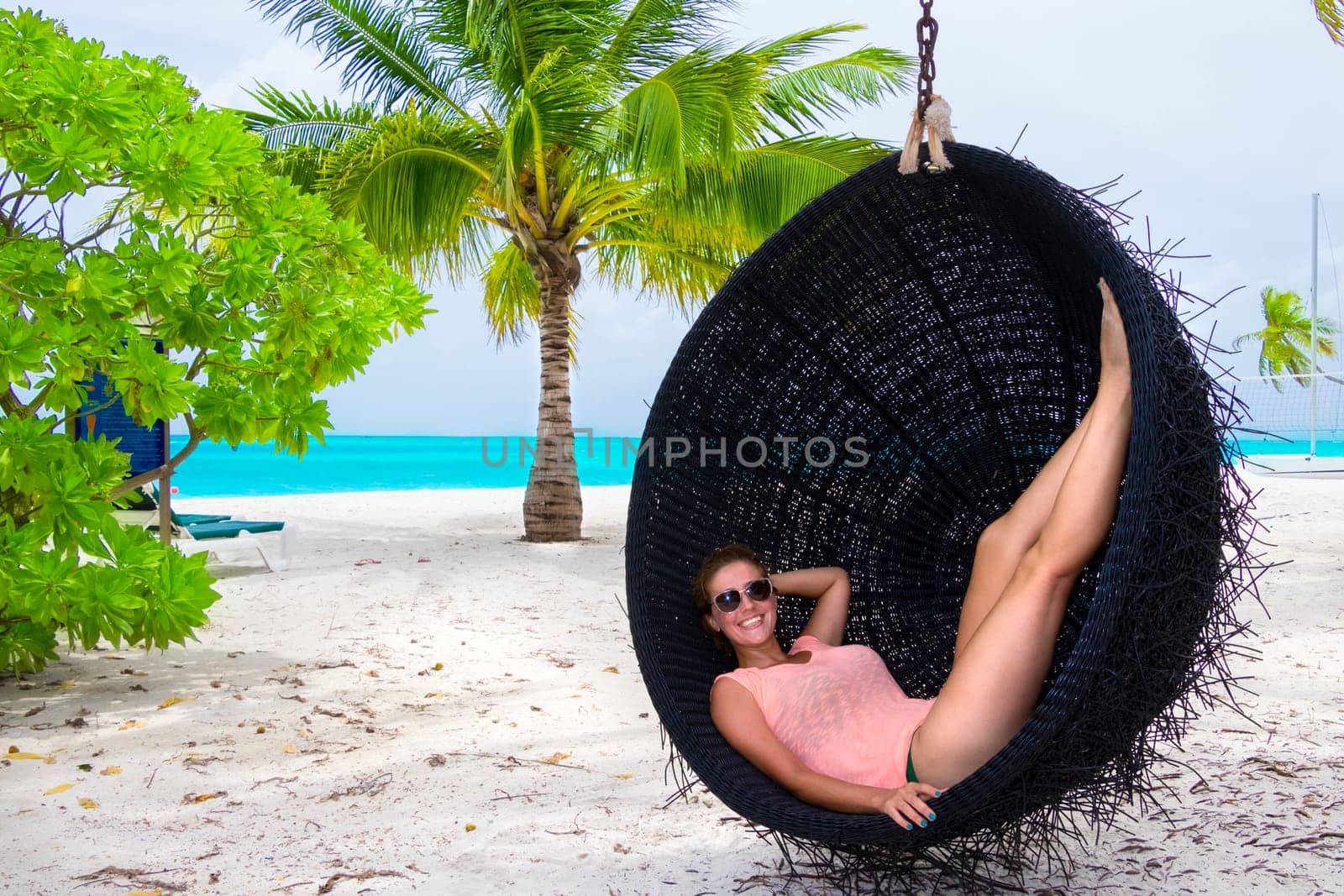 Beautiful woman relaxes on a swing on the dream beach