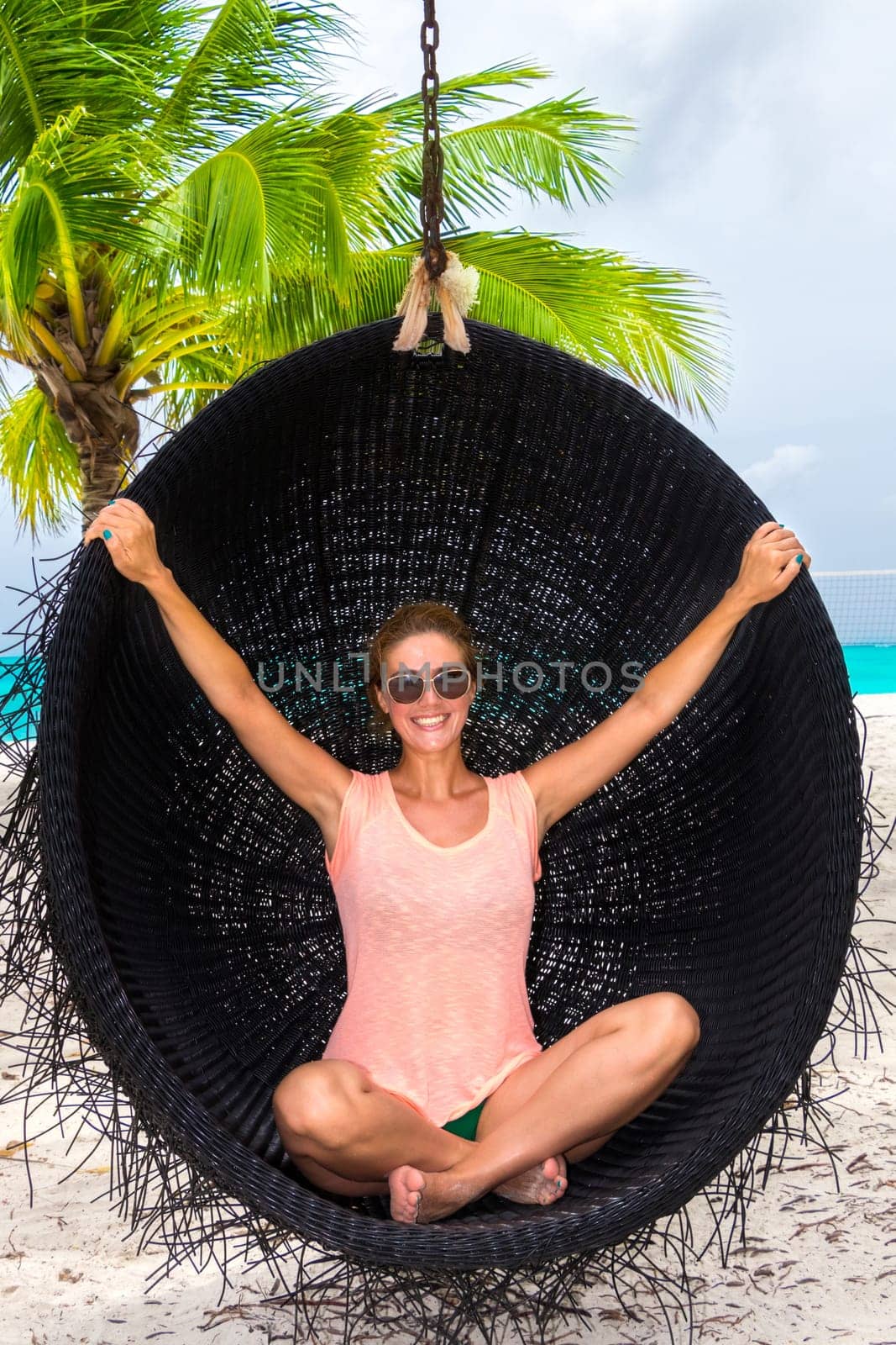 Beautiful woman relaxes on a swing on the dream beach