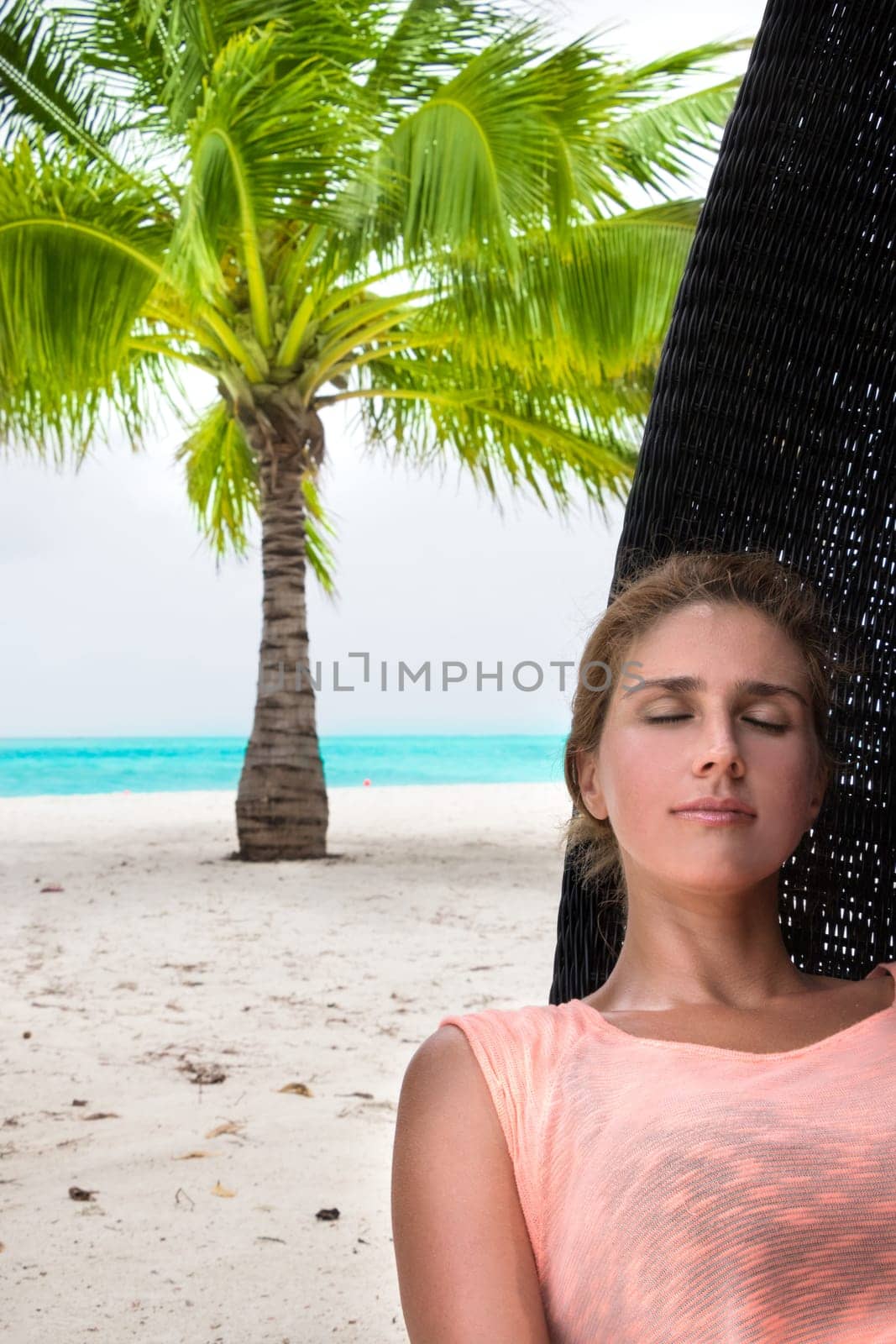 Beautiful woman relaxes on a swing on the dream beach
