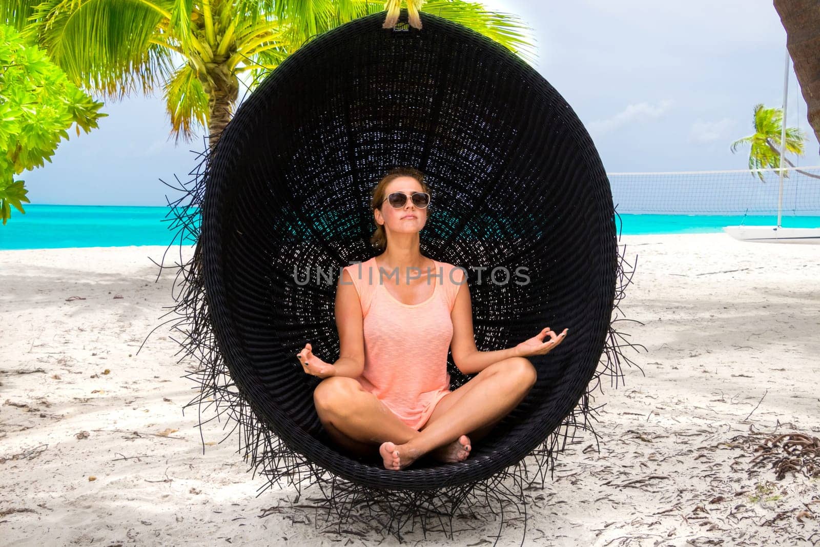 Beautiful woman relaxes on a swing on the dream beach