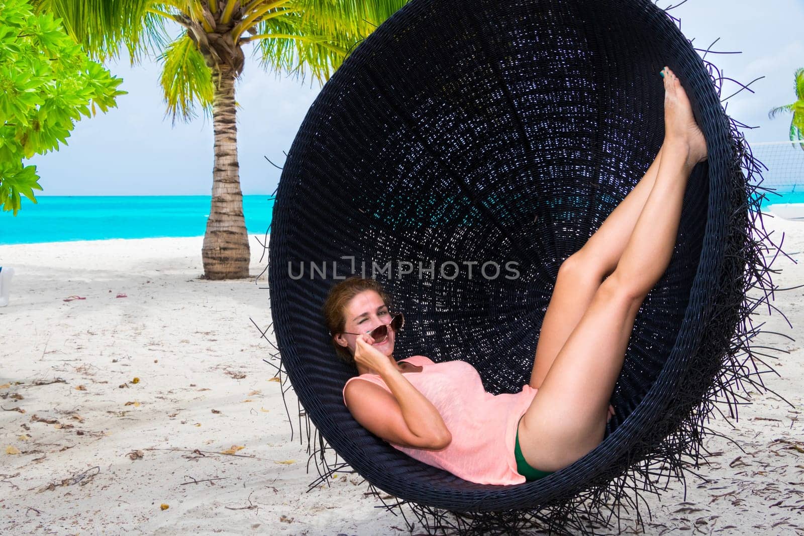 Beautiful woman relaxes on a swing on the dream beach