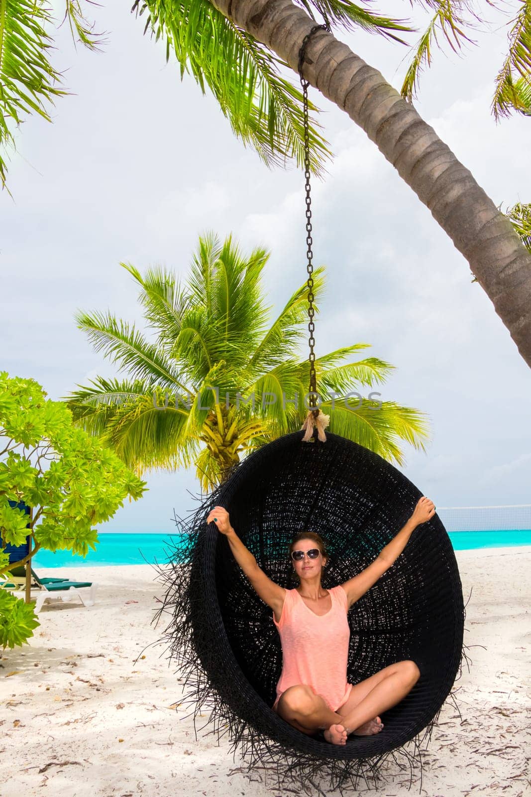 Beautiful woman relaxes on a swing on the dream beach