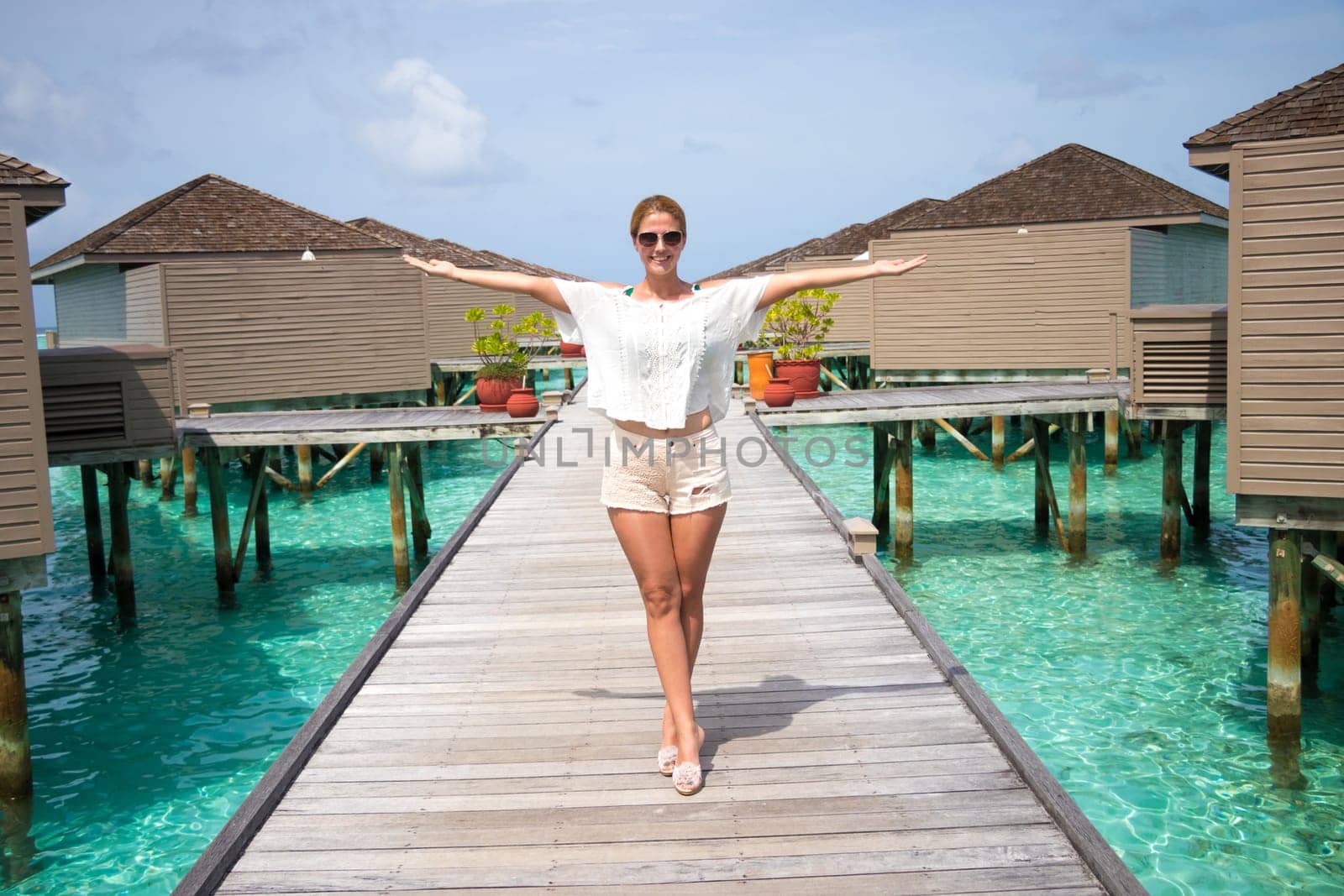 Beautiful woman in front of water villas on the wooden pier