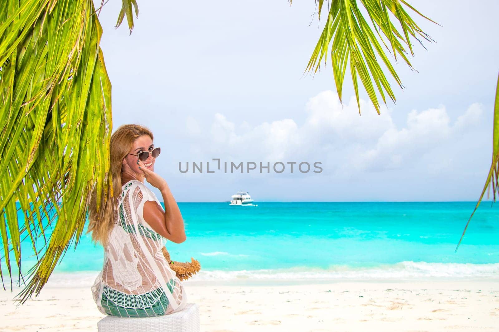Gorgeous woman behind a palm tree at the dream beach