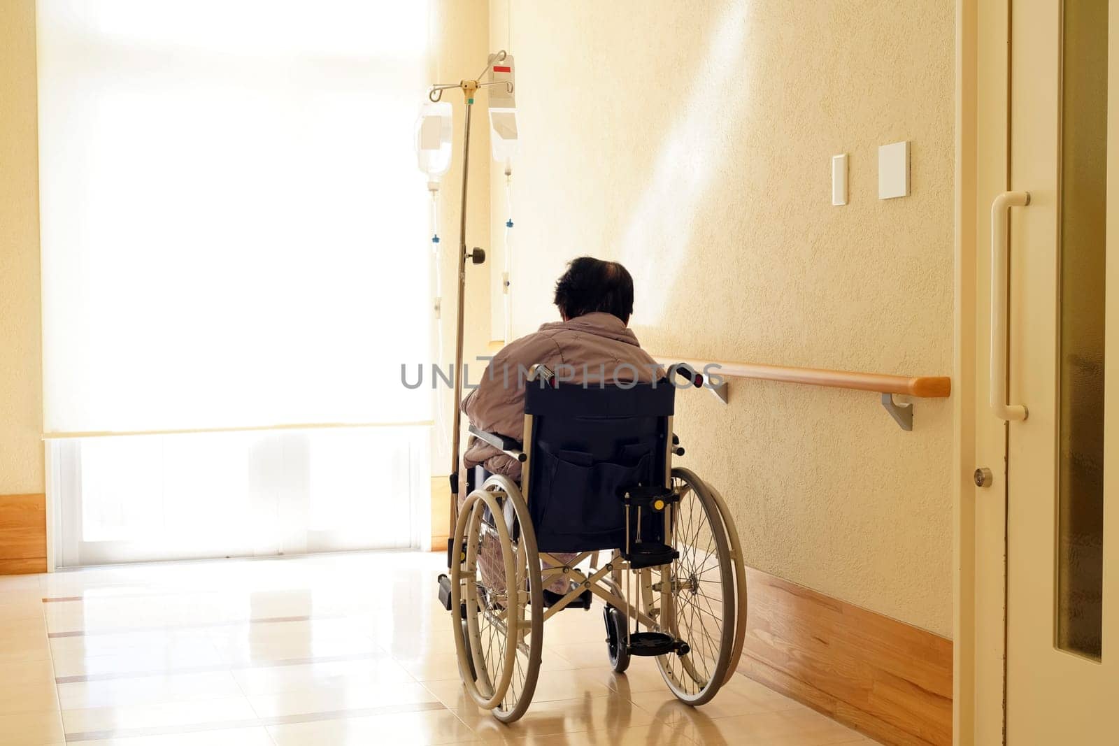 Back view of senior or elderly woman on wheelchair at hospital hallway