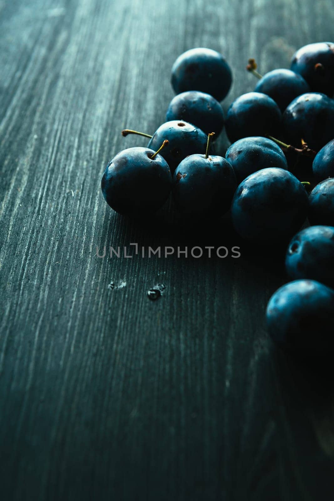 many fresh plums on black background close up.