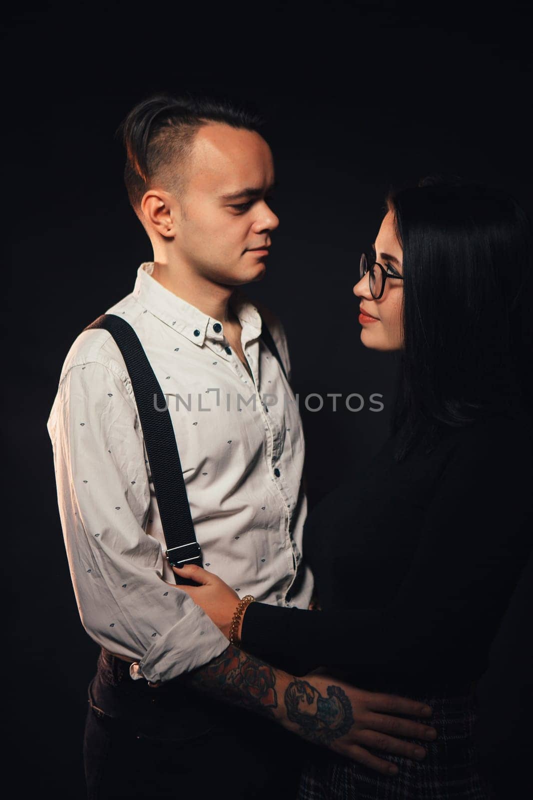 Couple in fashionable clothes on a dark background with smoke.