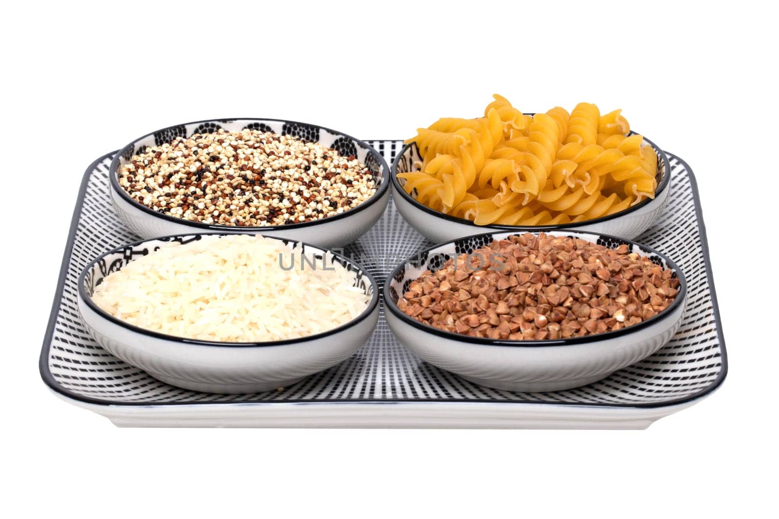 Vegetable food. Macro of a decorative plate with four bowls with buckwheat, noodles, rice and quinoa isolated on a white background. Healthy eating.