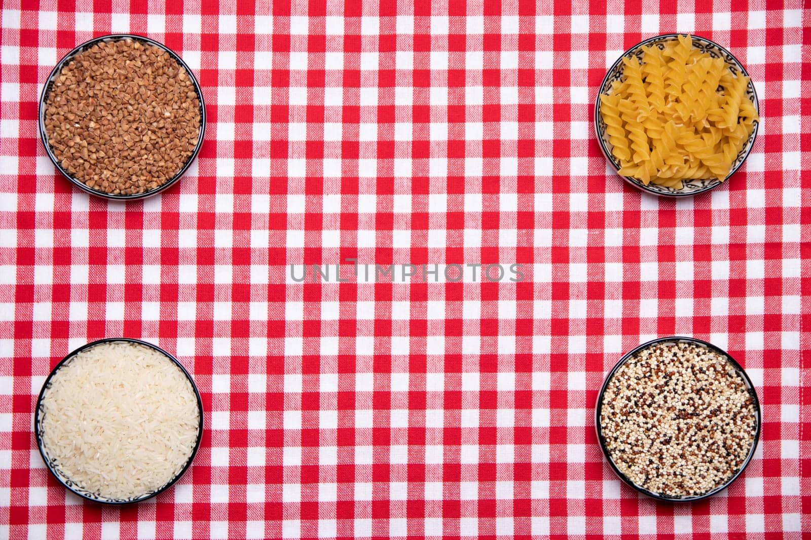 Vegetable food. A frame of four bowls with buckwheat, noodles, rice and quinoa on a red checkered tablecloth. Healthy eating. Top view with space for product montage.