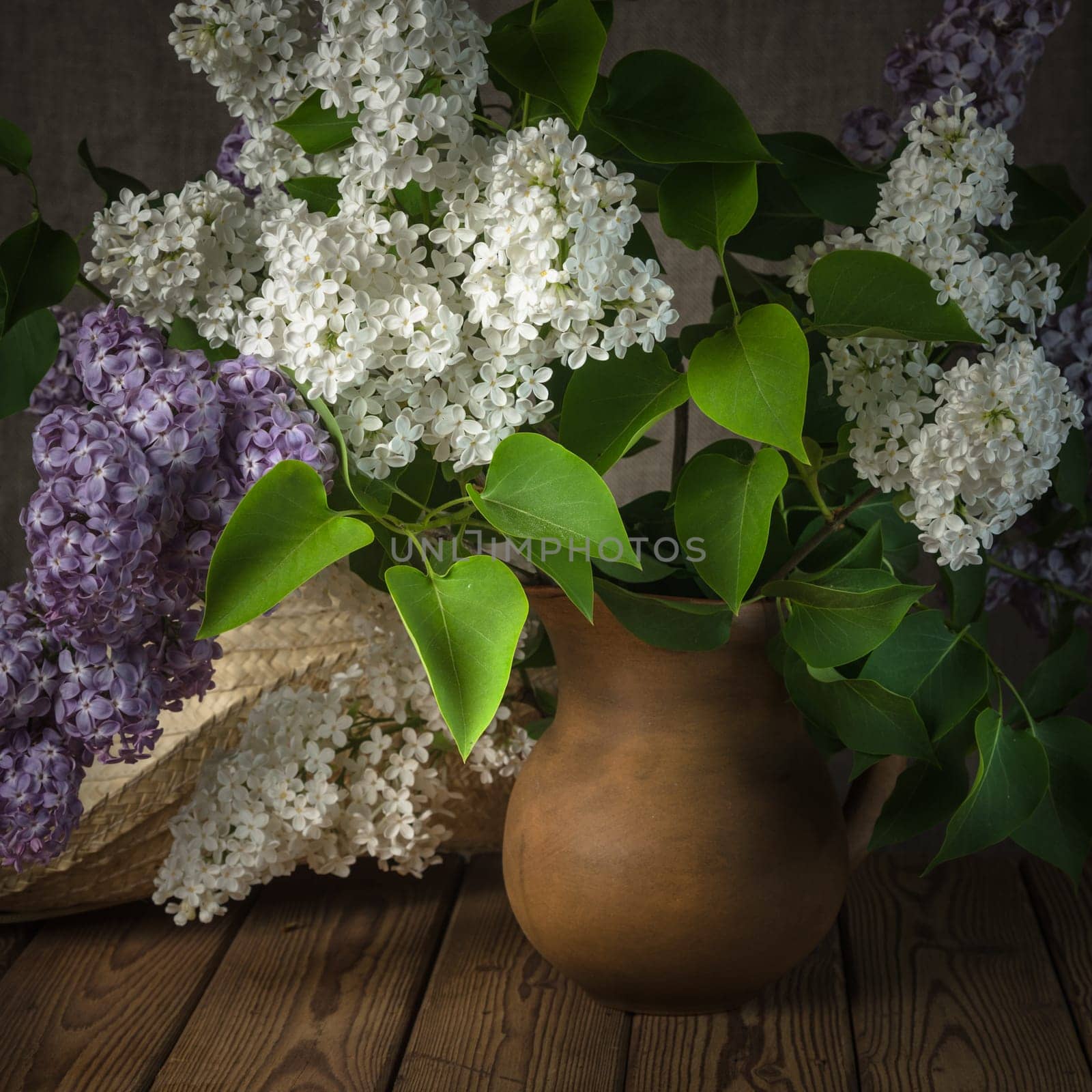 Still-life with a bouquet of lilacs and a straw hat, close-up