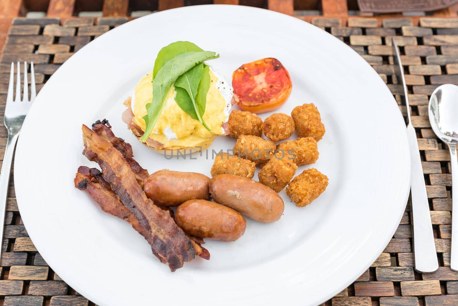 Delicious breakfast with eggs Benedict, bacon, sausage, and potato hash brown