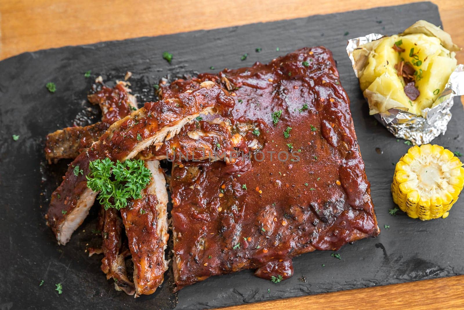 Grilled Barbecued Pork Baby Back Ribs with baked potato and grilled sweet corn