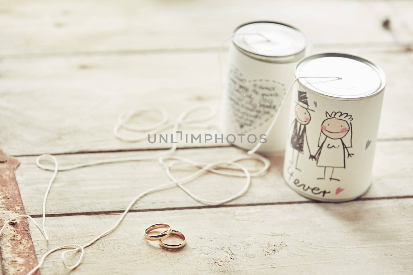 Wedding cans decoration with ribbons and the wedding rings ready for marriage ceremony, sitting on wooden background and viewed from high angle
