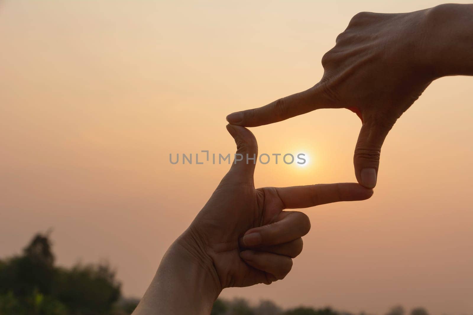 Hands making frame with sunset. Close up of woman hands making frame gesture.