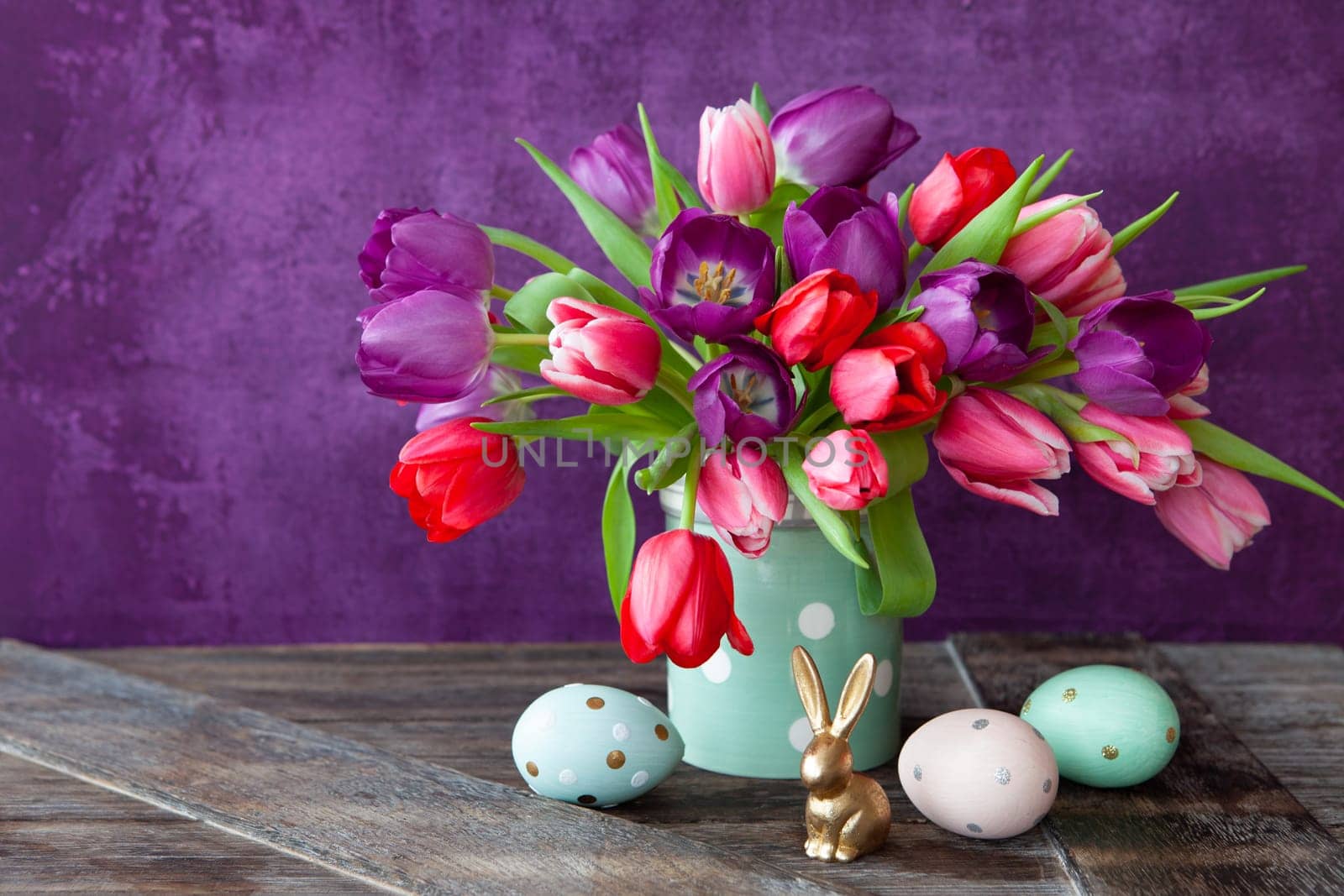 Colorful tulips in spring with easter decorations in front of purple background