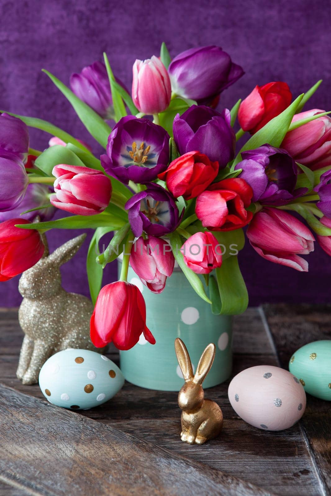 Colorful tulips in spring with easter decorations in front of purple background