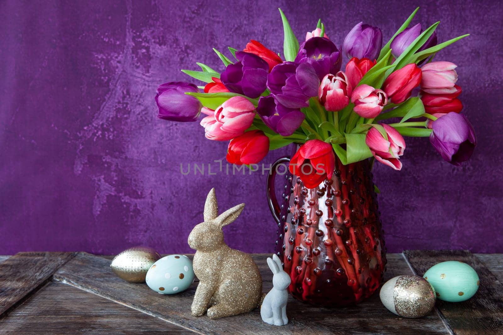 Colorful tulips in spring with easter decorations in front of purple background