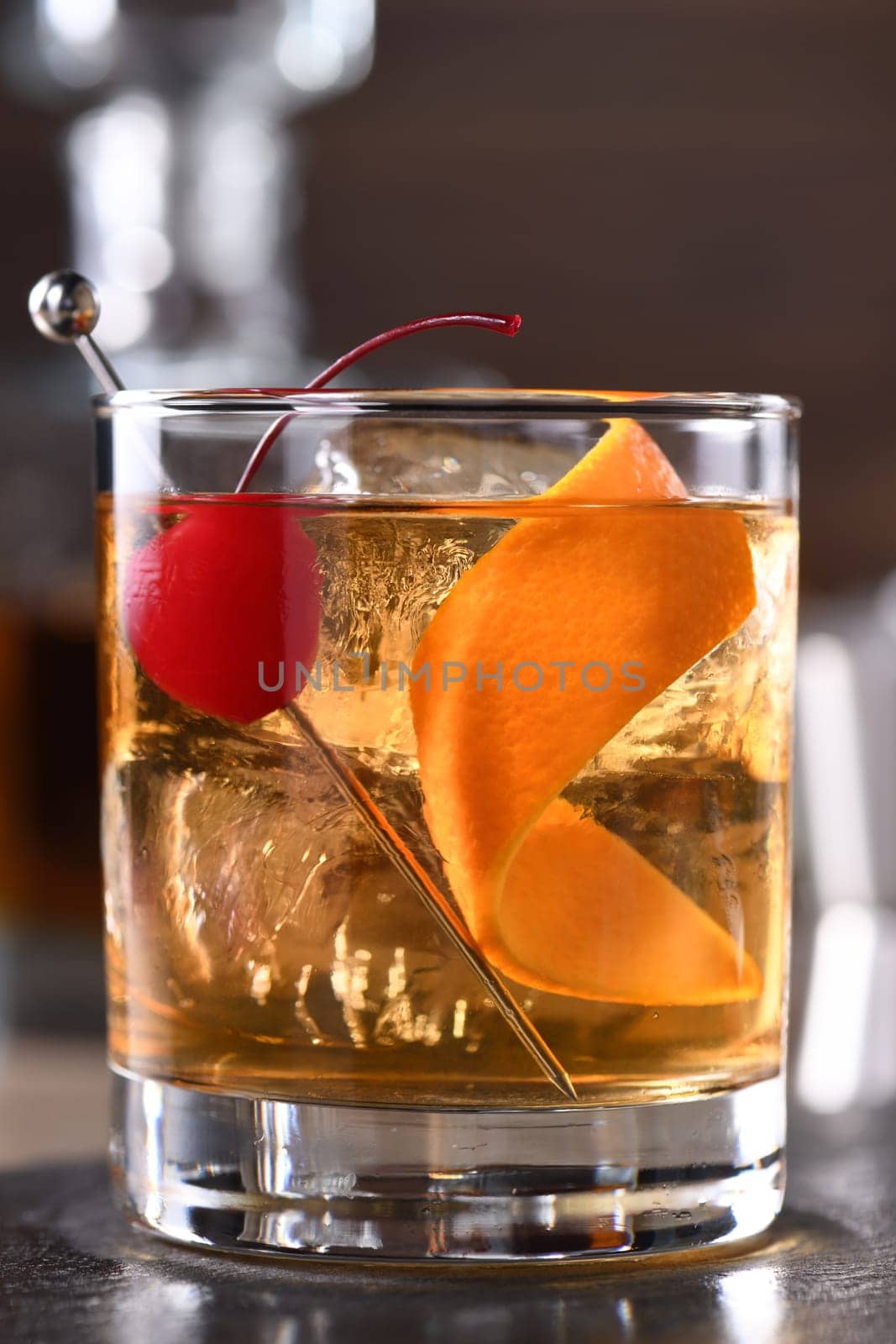 Cocktail Old Fashioned is an old-fashioned sophistication of whiskey and sweet syrup. Served with ice, orange zest and Maraschino cherry. 