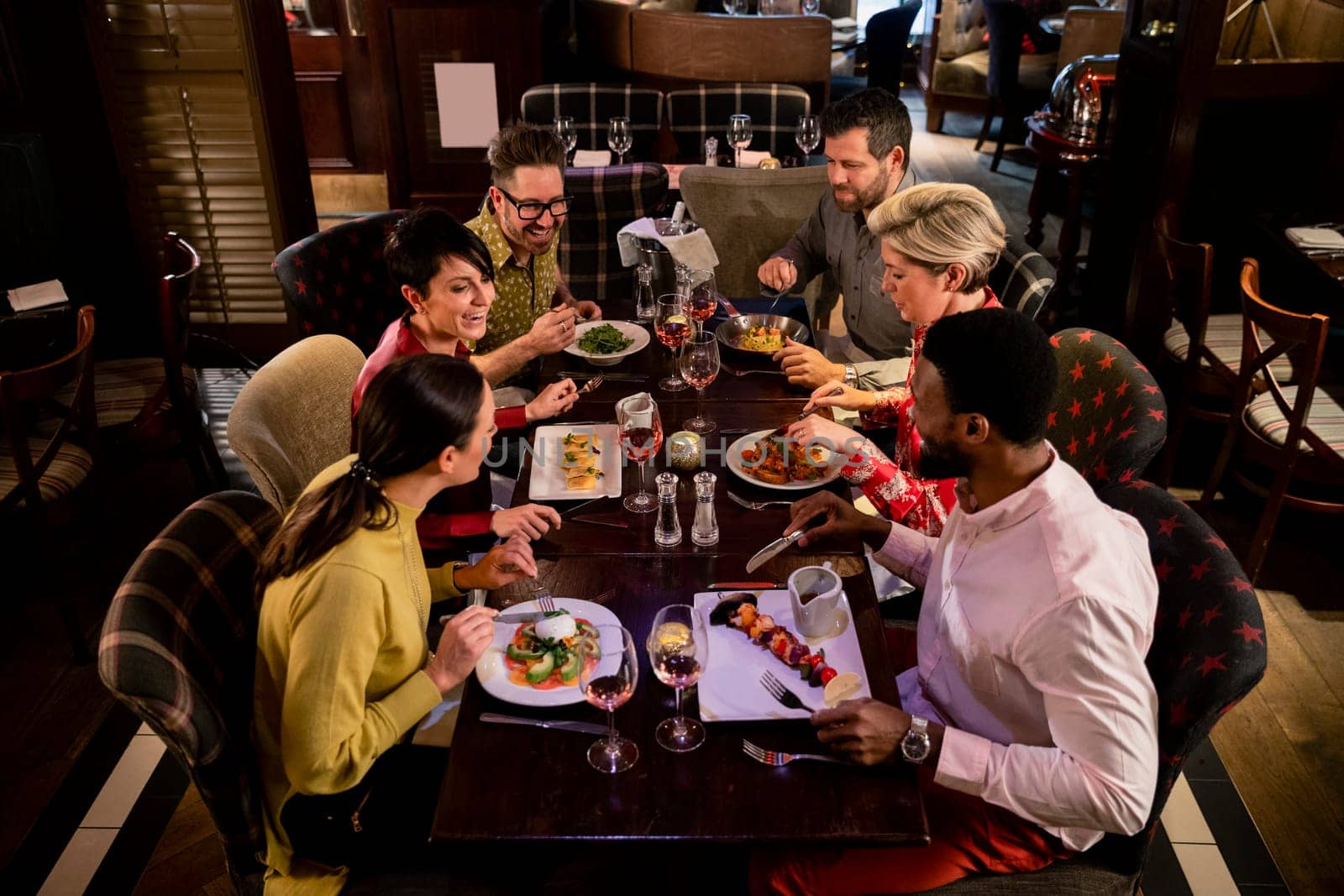 Small group of friends enjoying a meal in a restaurant. They are sitting at a table as they eat their food.