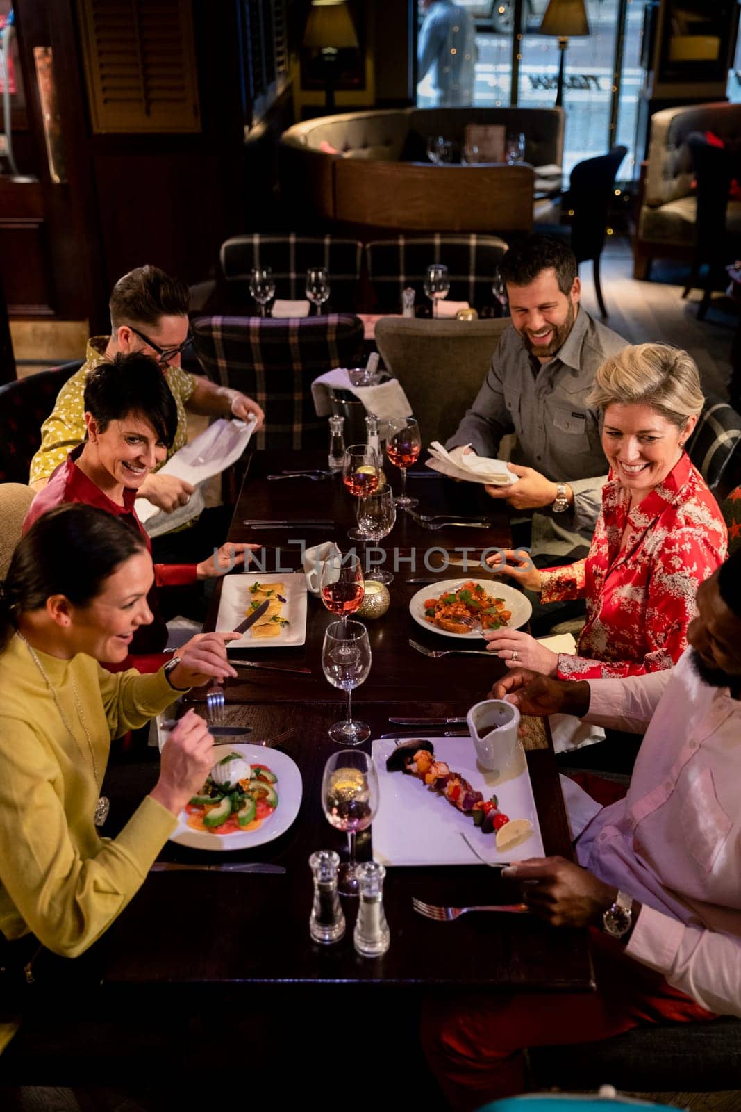 Small group of friends enjoying a meal in a restaurant. They are sitting at a table as they eat their food.