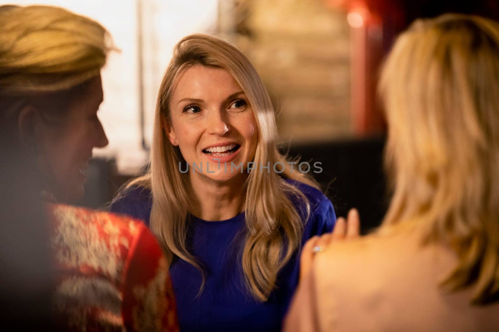 Over the shoulder view of a mature woman talking and smiling with her friends.