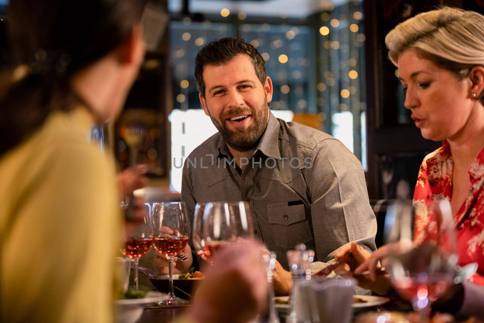 Mid adult man sitting at a restaurant table with some friends and enjoying a meal.