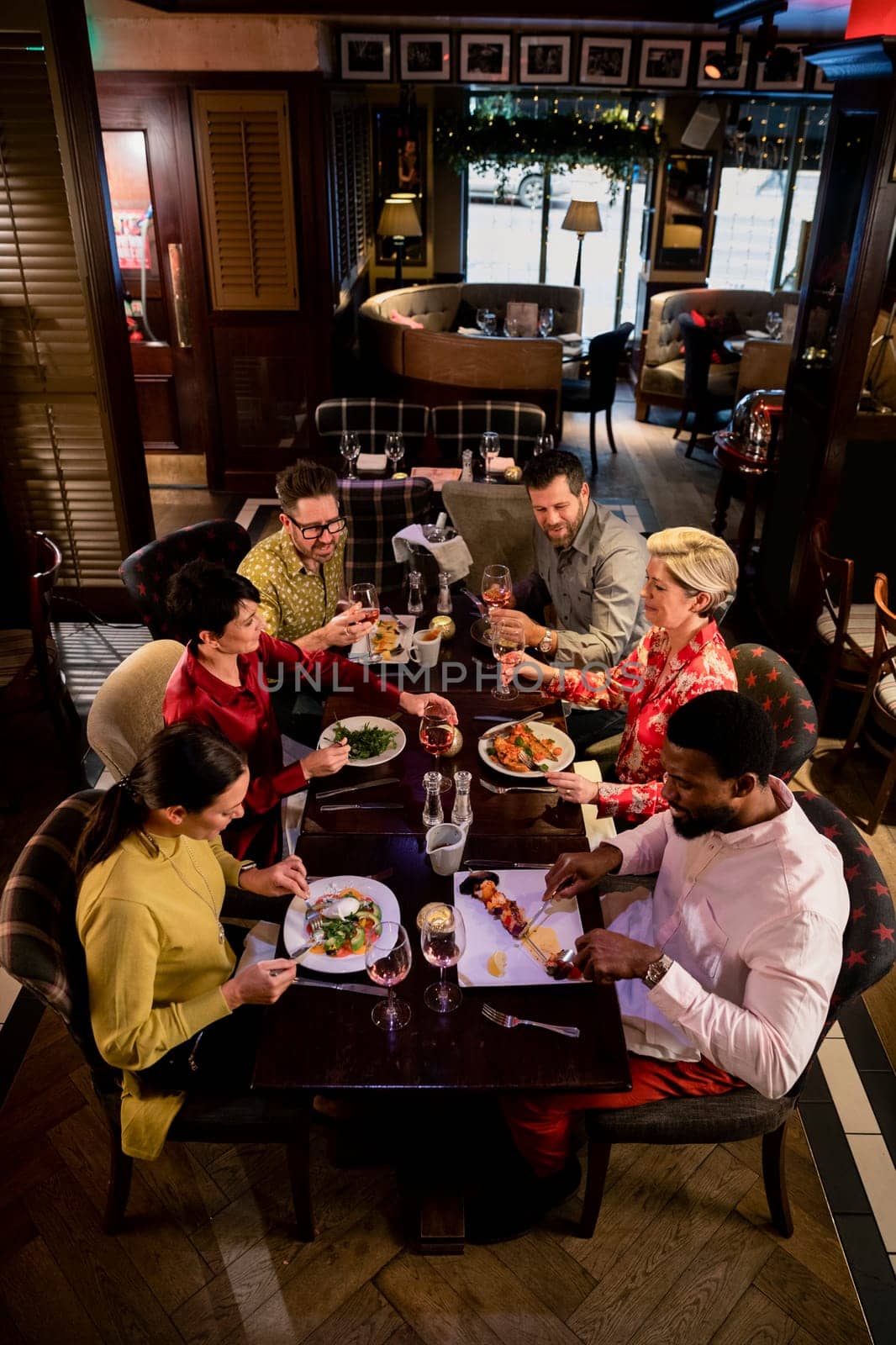 Small group of friends enjoying a meal in a restaurant. They are sitting at a table as they eat their food.