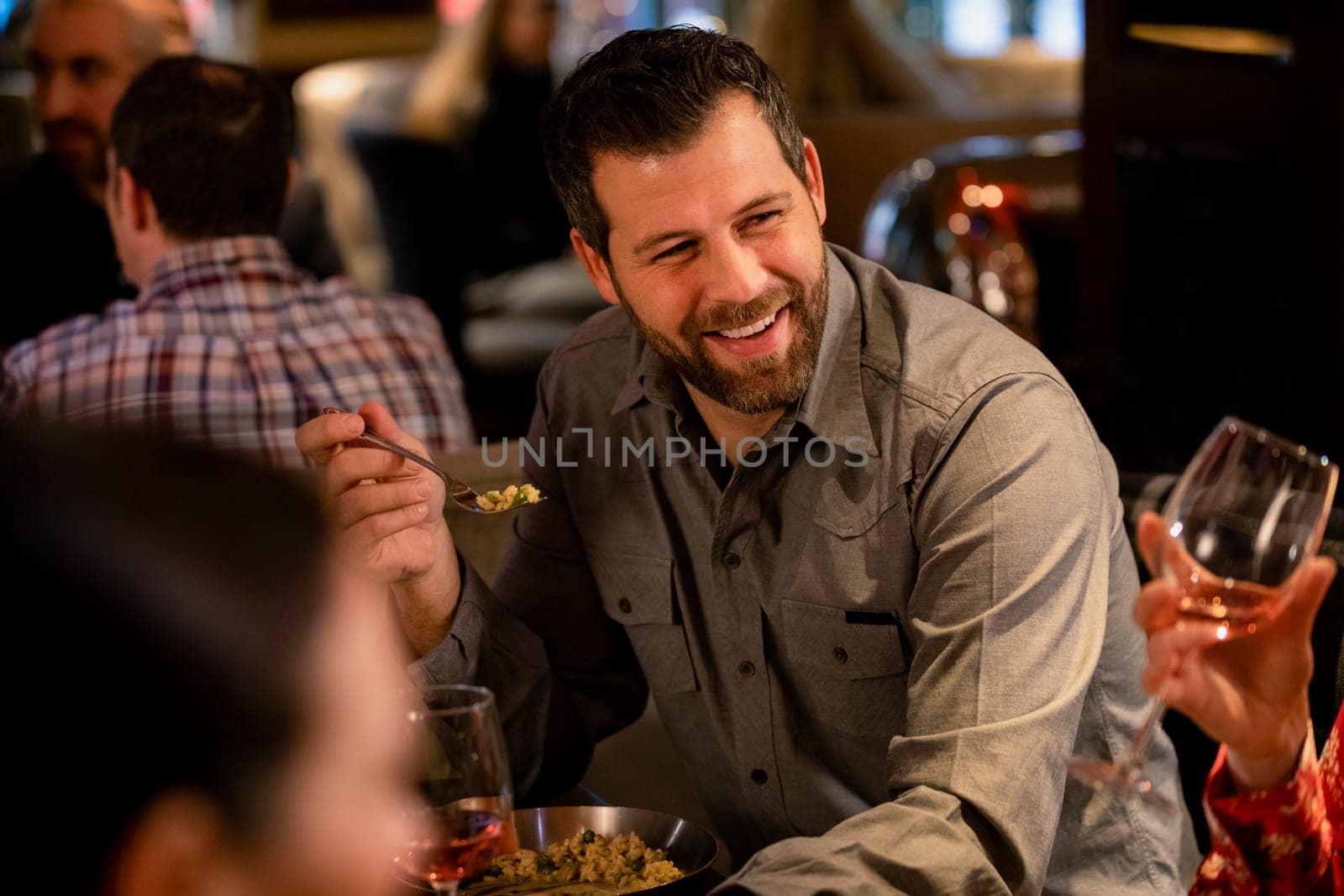 Mid adult man enjoying food while in a restaurant with some friends.