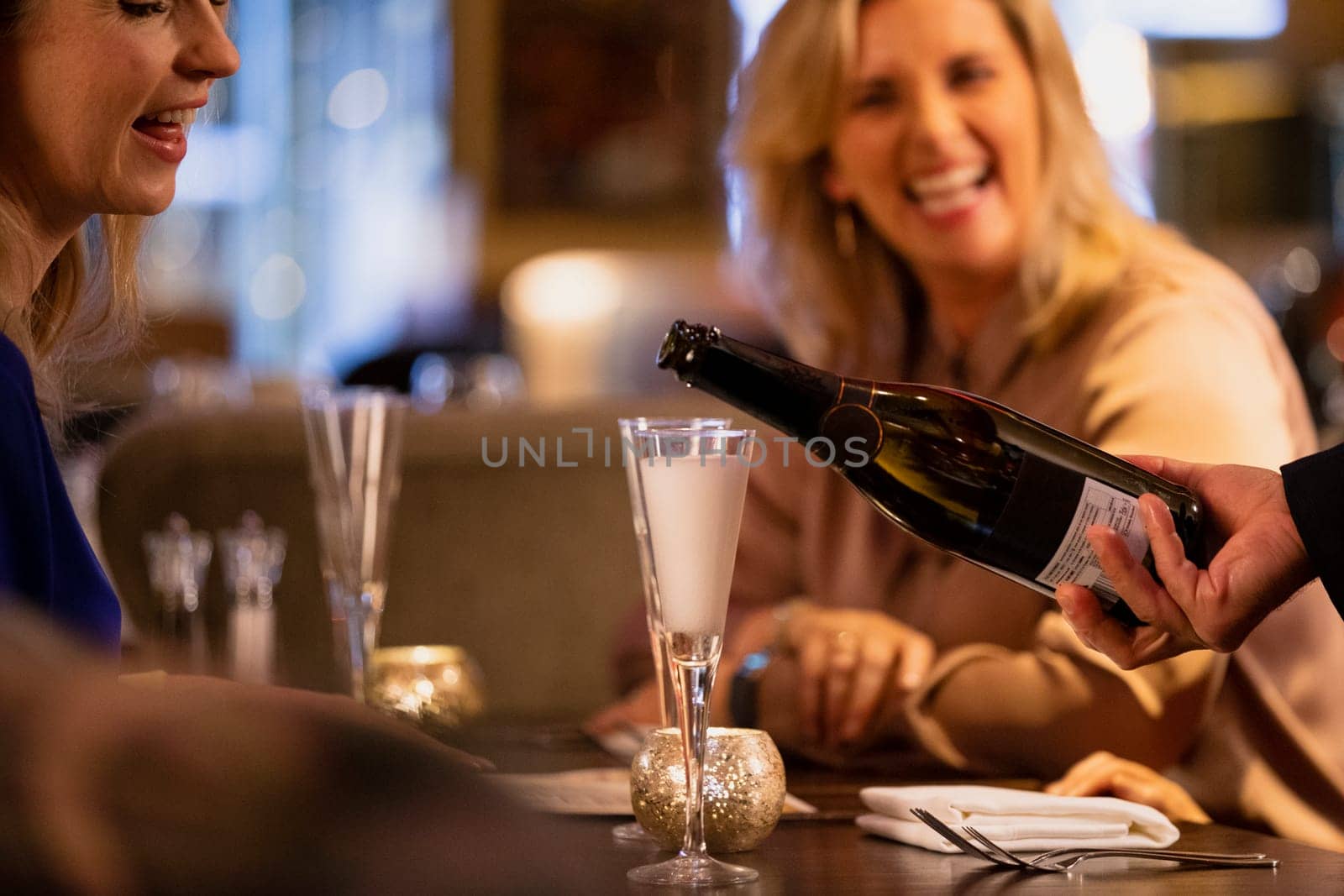 Close-up of a unrecognisable waiter pouring a glass of prosecco.