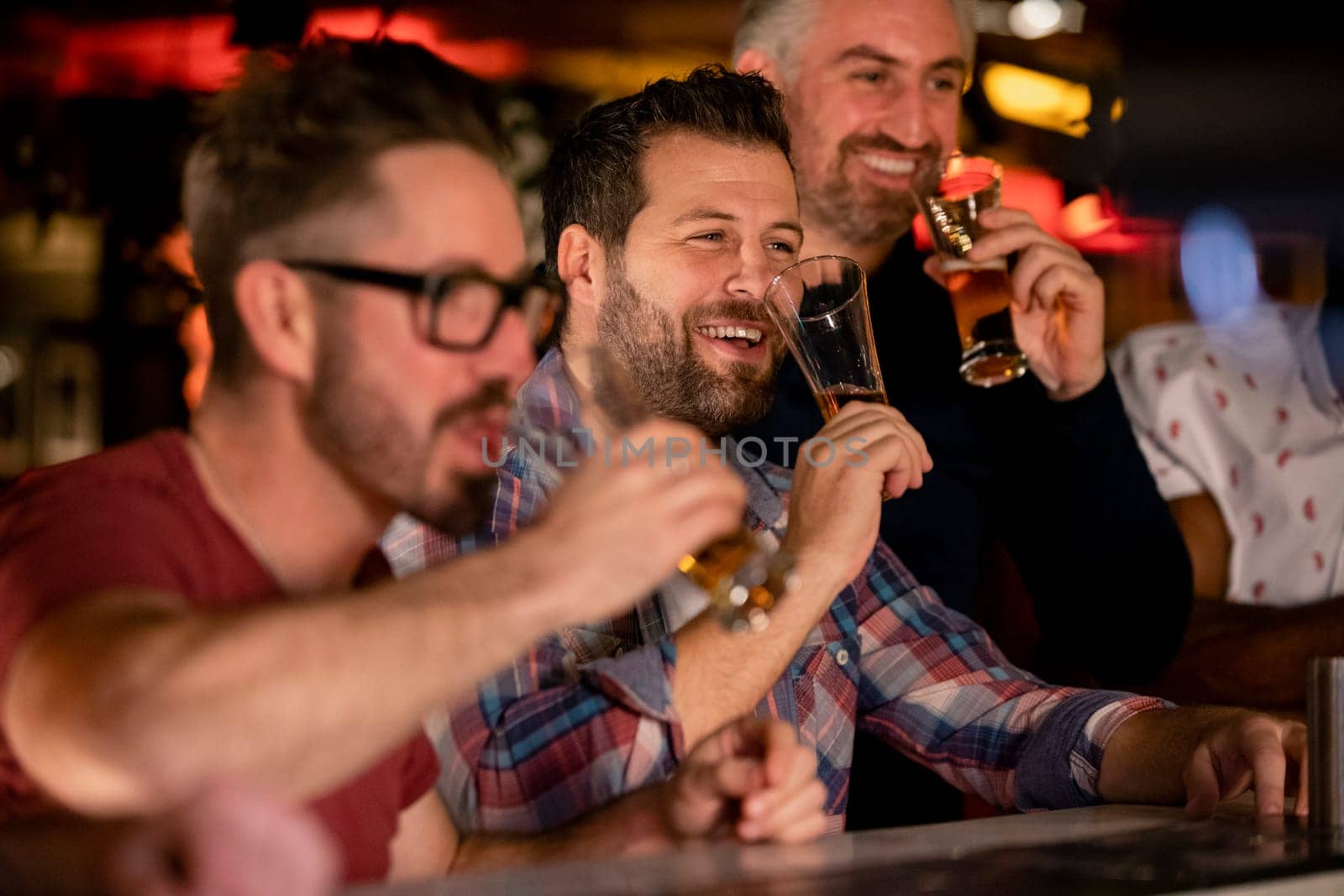 Three mid adult male friends enjoying a beer together in a bar.