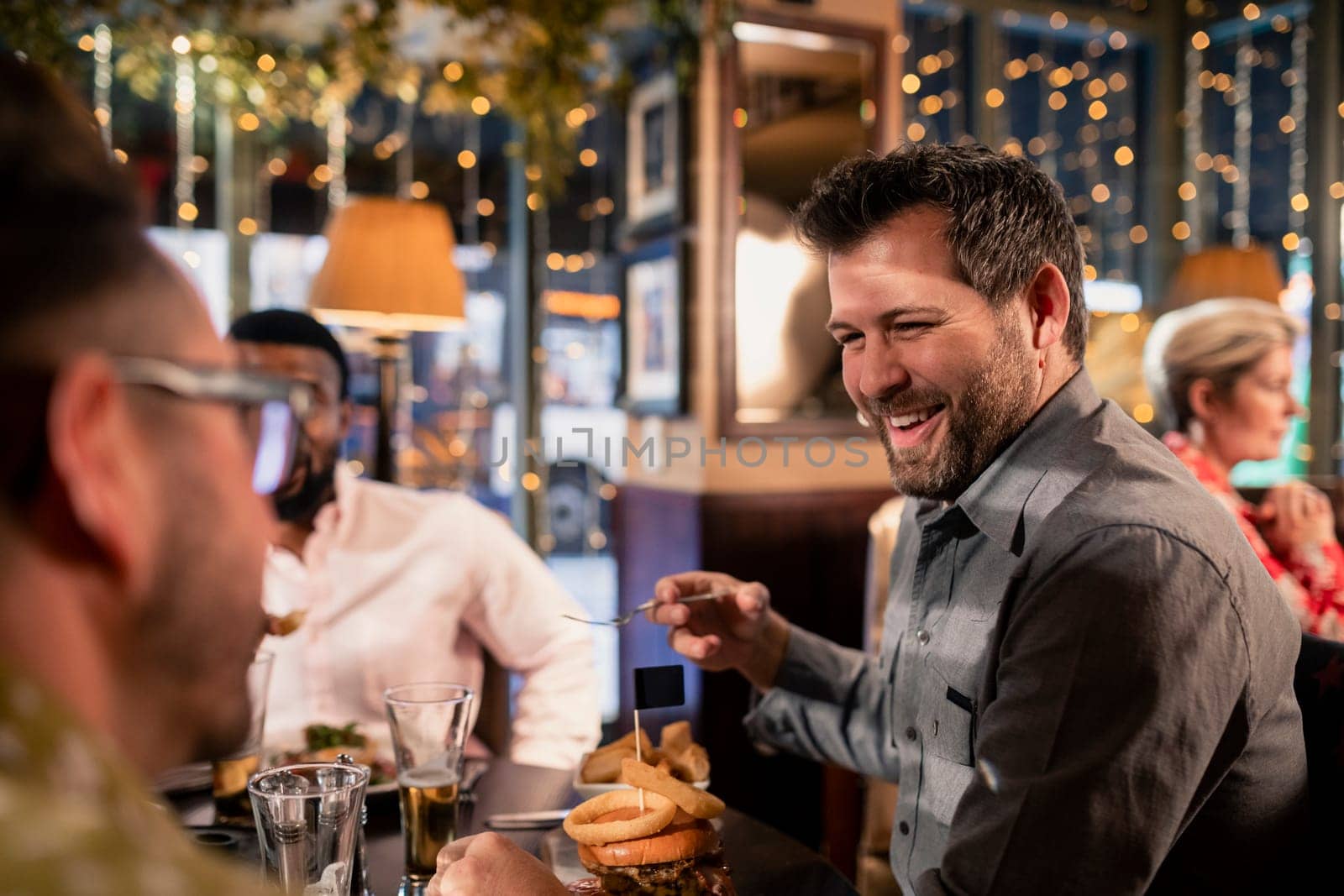 Small group of mid adult male friends enjoying some food in a restaurant. They are talking and enjoying each others company.