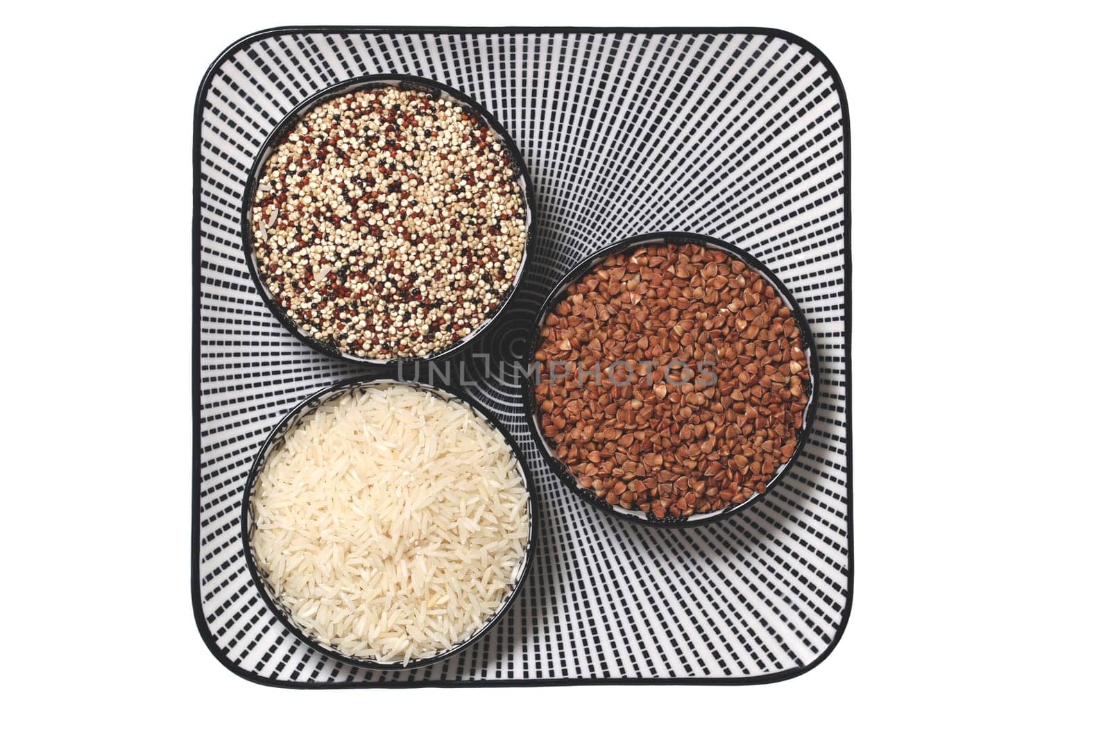 Vegetable food. Macro of a decorative plate with three bowls with buckwheat, rice and quinoa isolated on a white background. Healthy eating. Top view.