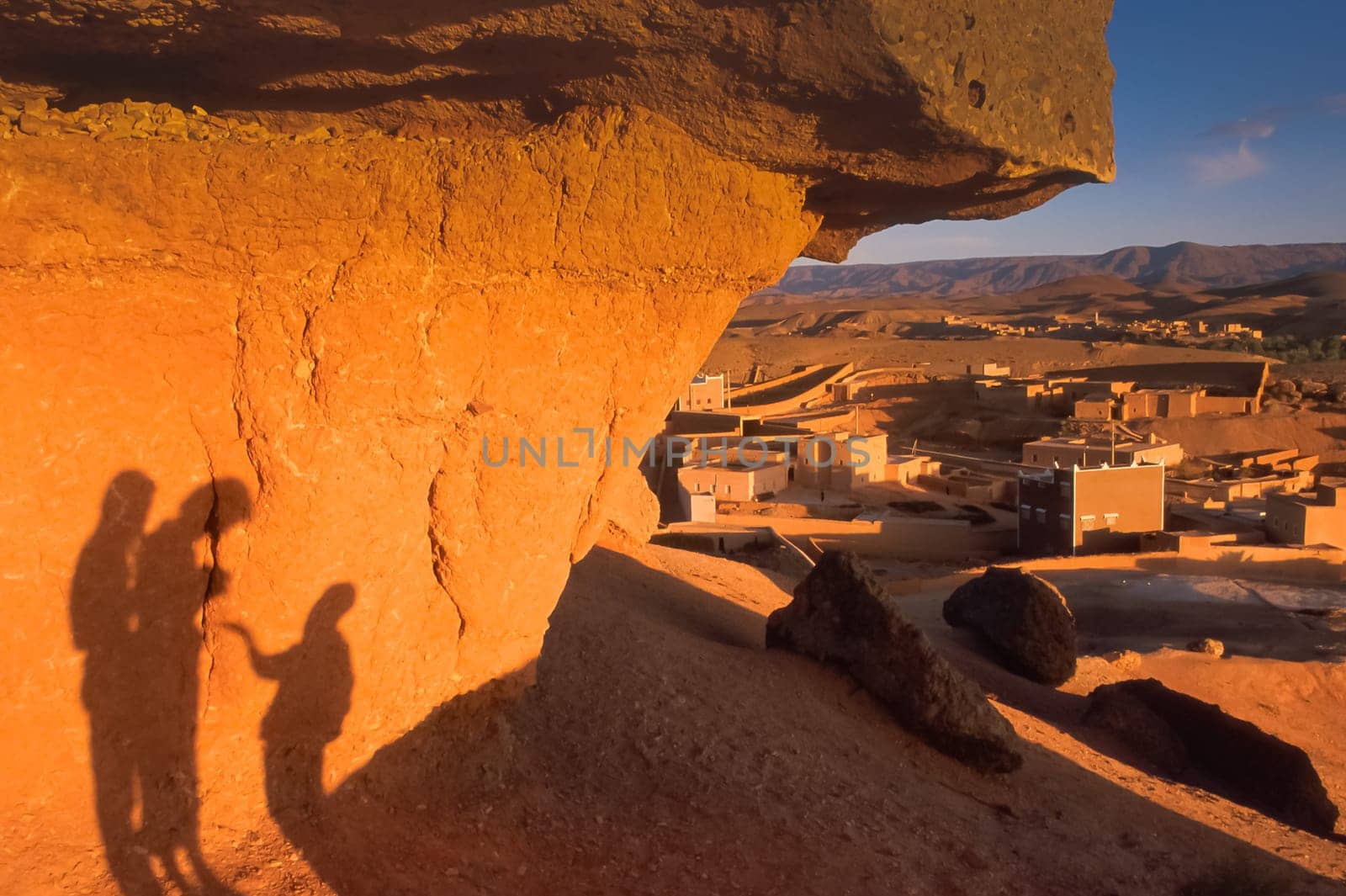 A gesture of charity concept. Shadow of two adults and one child projected on the rock at sunset, horizontal image with side light, Ouarzazate Province, Morocco