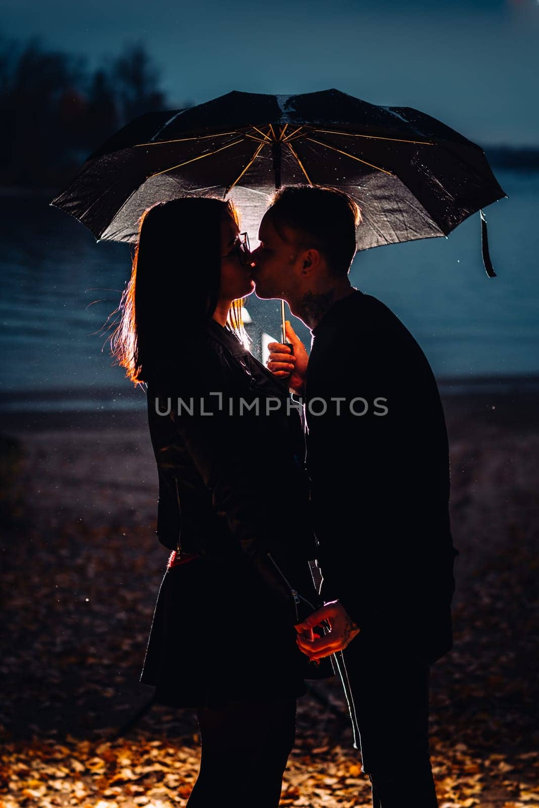 young man and woman under an umbrella and rain.