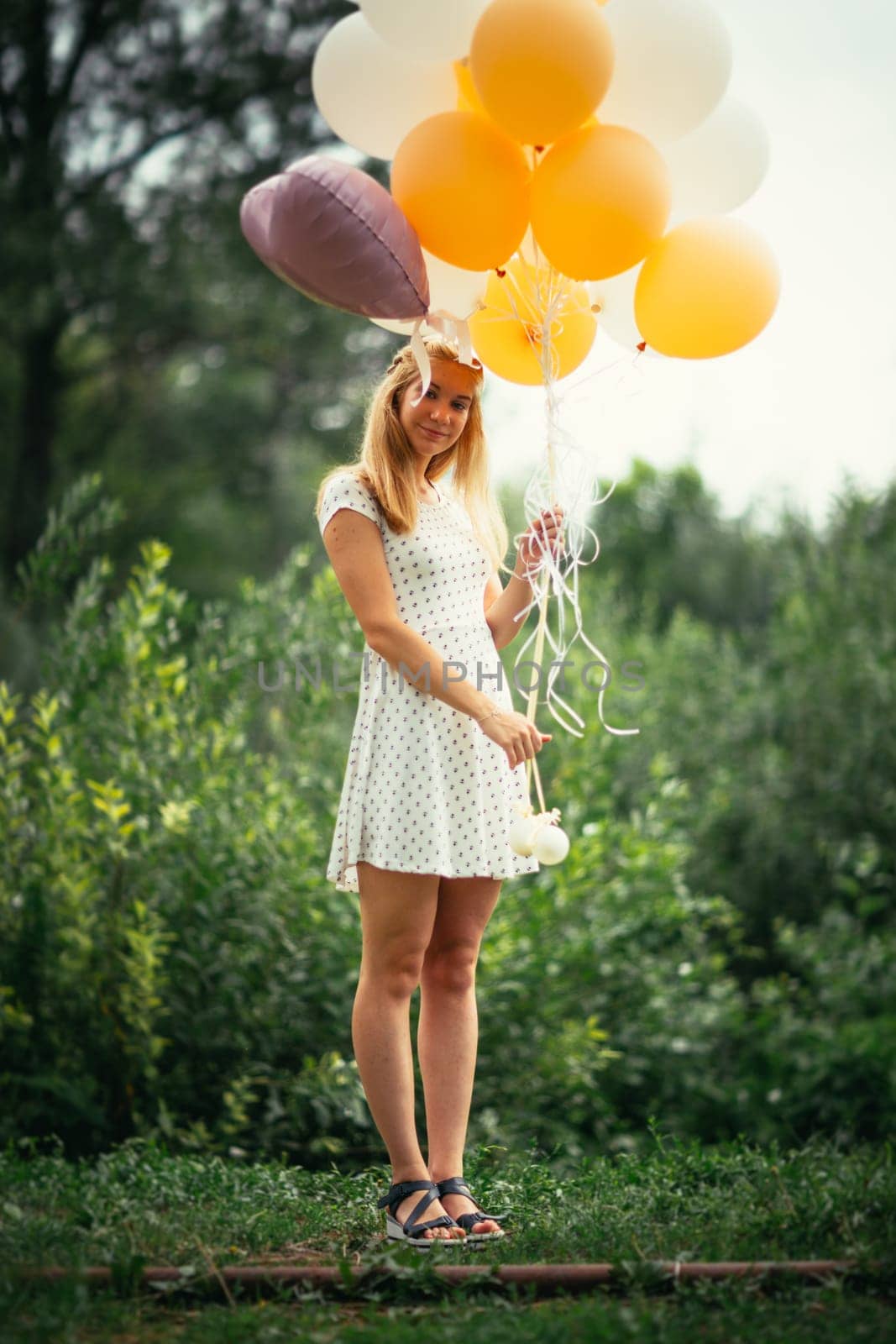young girl with balloons on nature background.