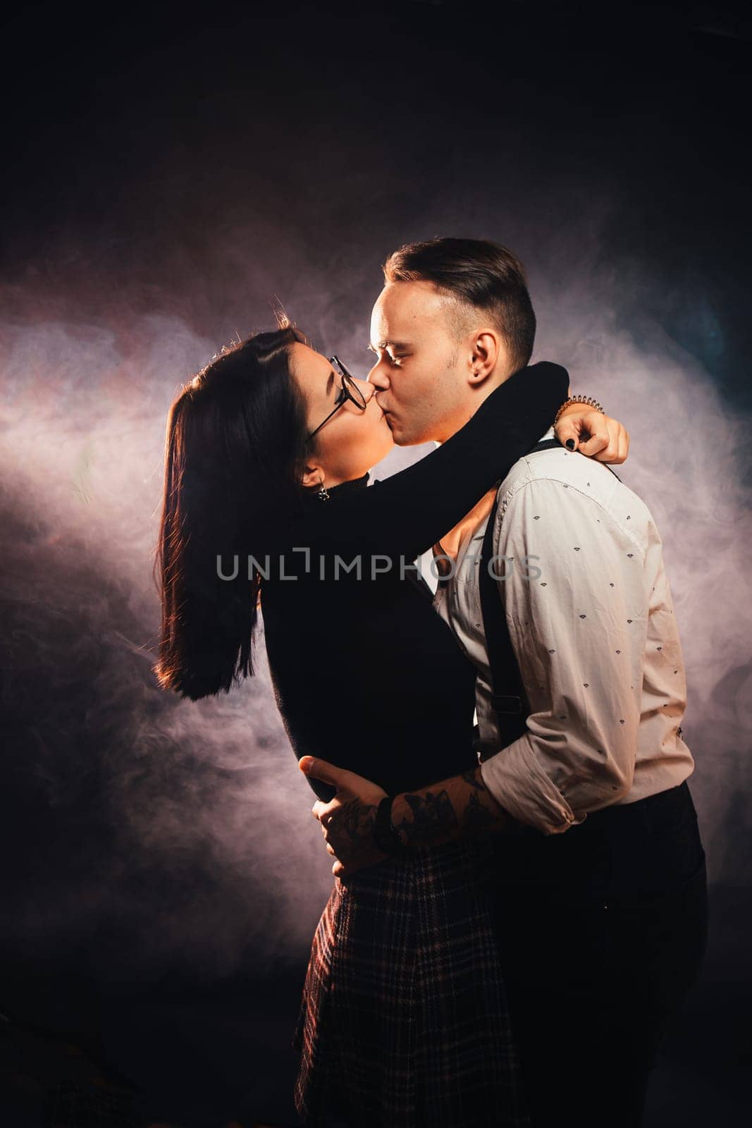 Couple in fashionable clothes on a dark smoky background.