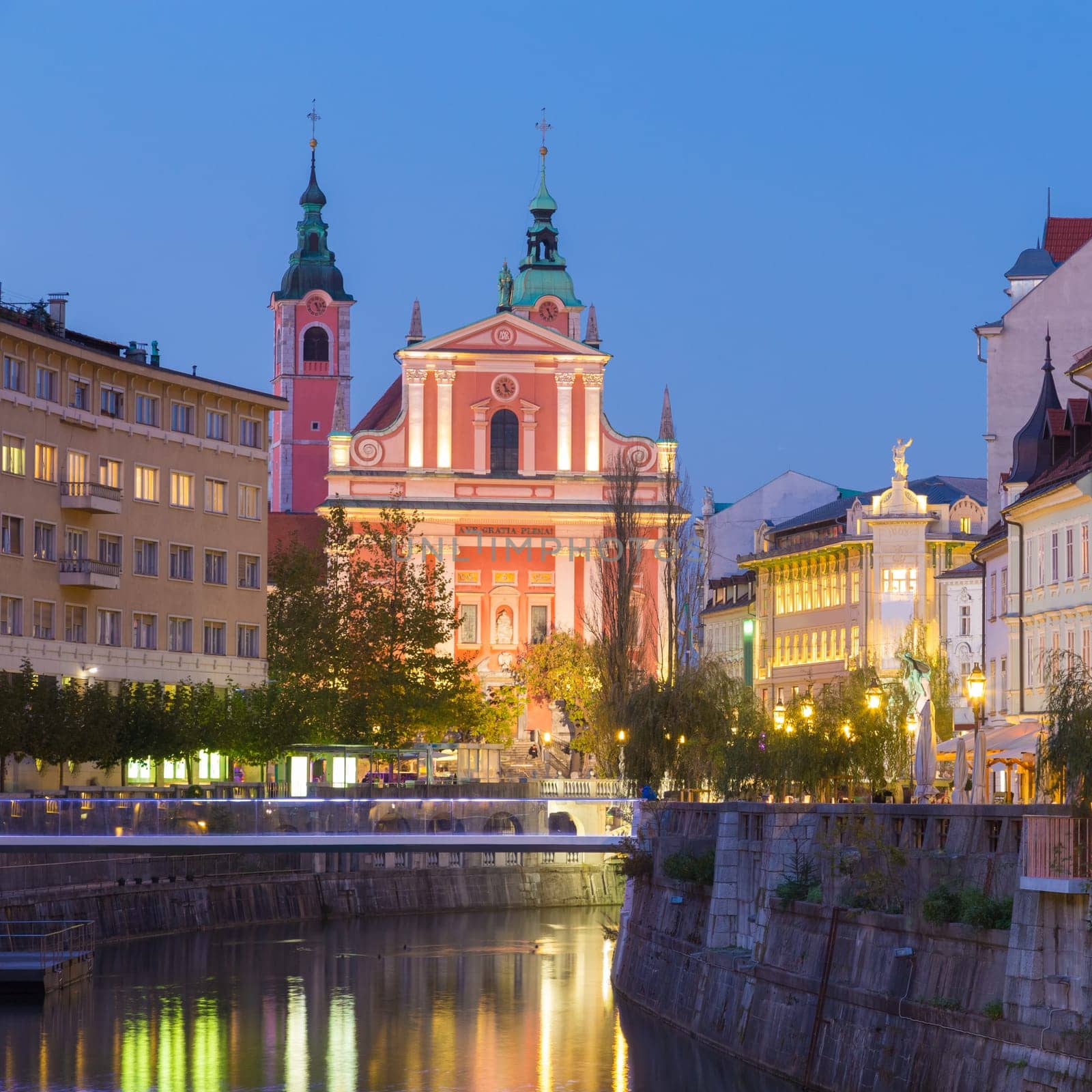 Romantic medieval Ljubljana's city center, capital of Slovenia, Europe. Night life on the banks of river Ljubljanica where many bars and restaurants take place. Franciscan Church in background