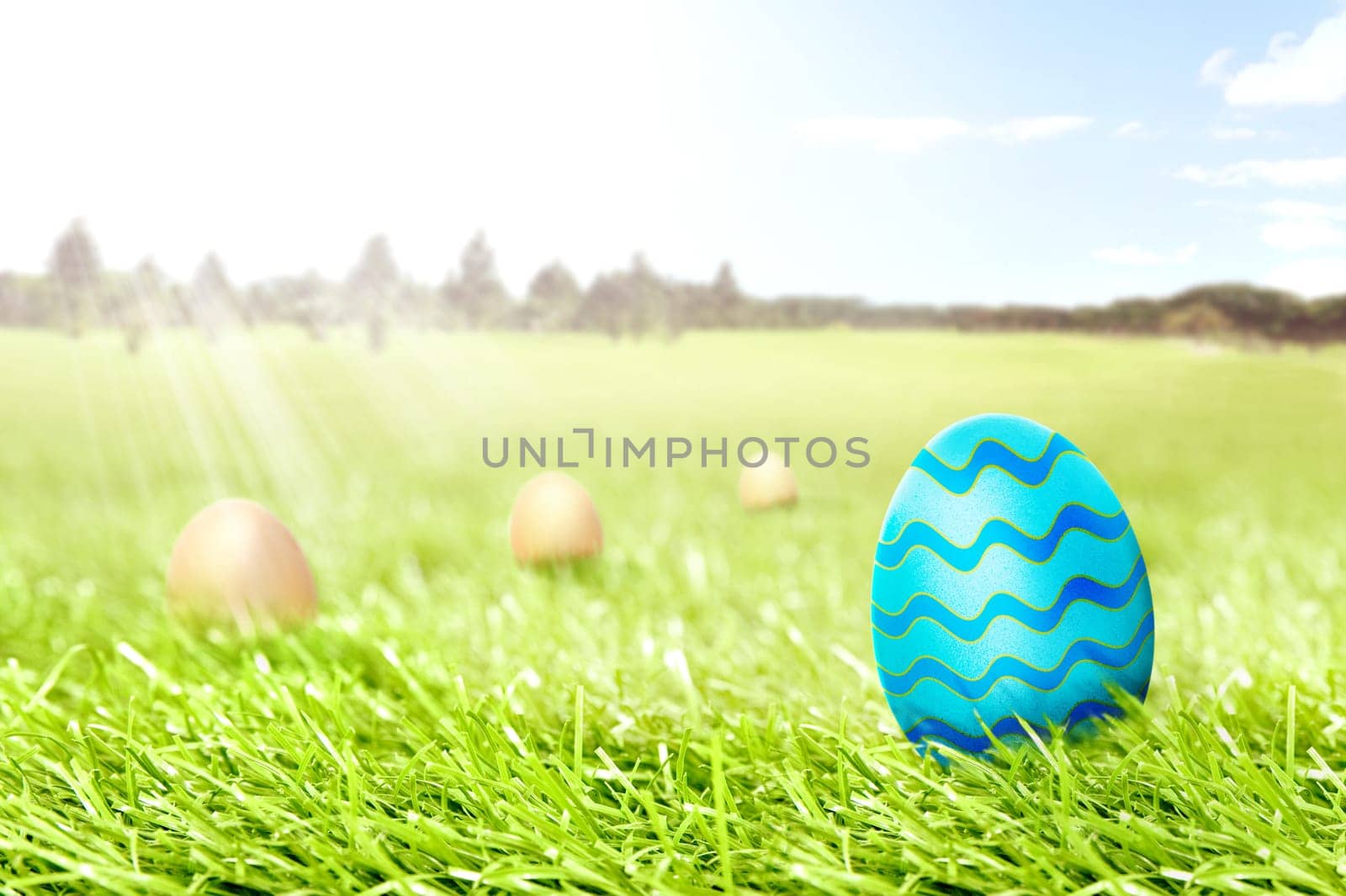 Colorful easter eggs hidden in the grass field with trees and blue sky background. Happy Easter