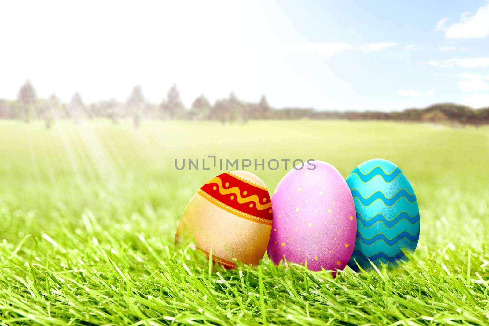 Colorful easter eggs on the grass field with trees and blue sky background. Happy Easter
