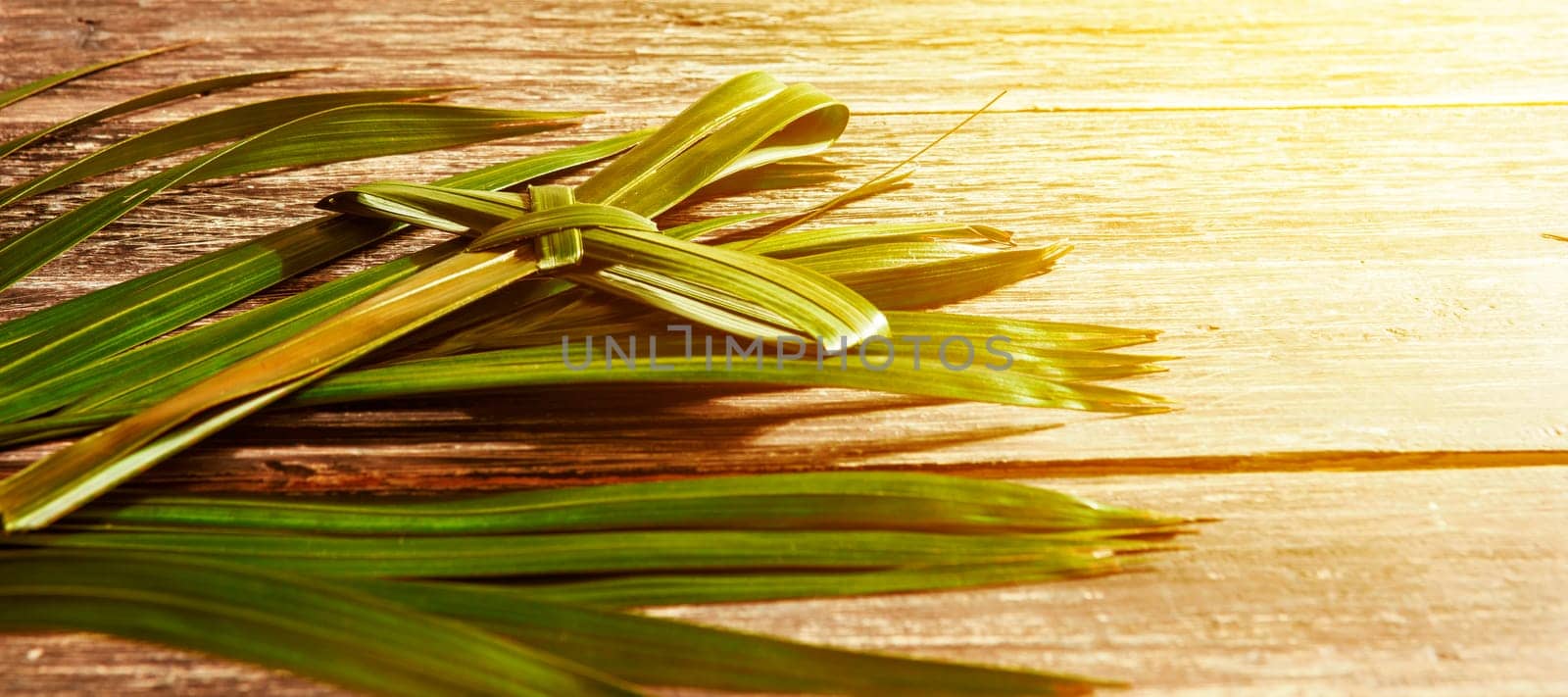 Closeup view of cross shape of palm leaf and palm branches with ray in wooden background. Palm Sunday concept