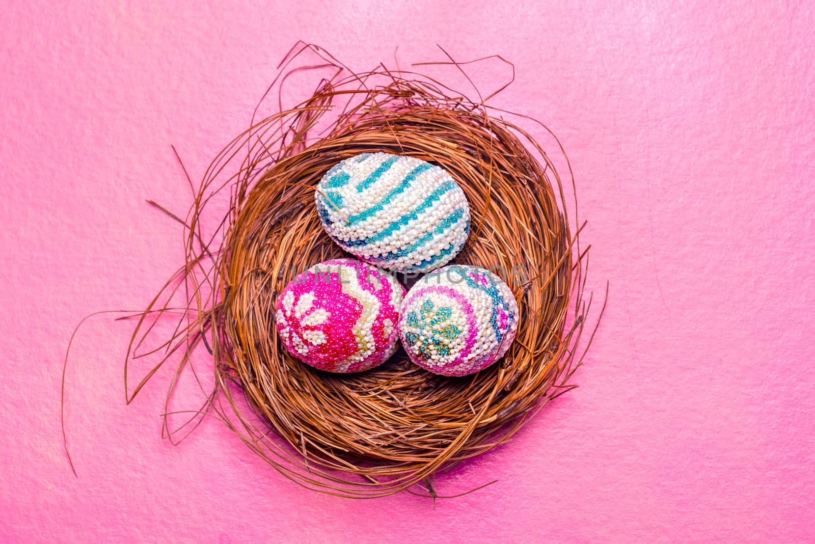 Close up view of Colorful easter eggs in the nest with pink background. Happy Easter