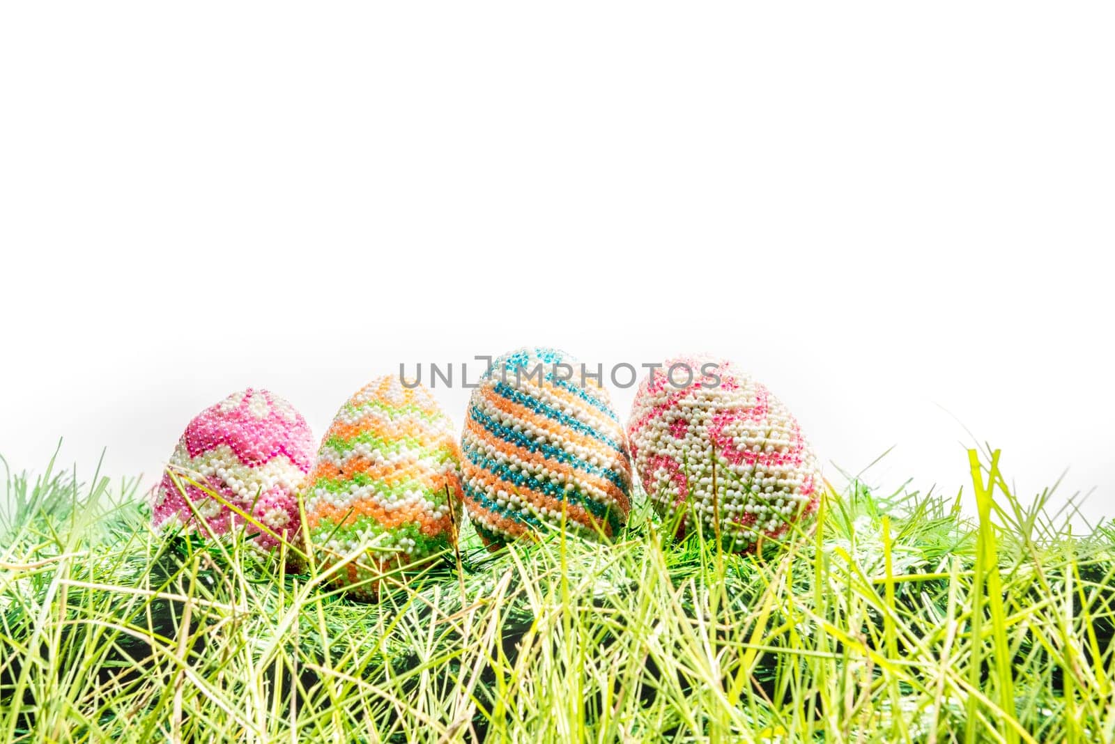 Colorful easter eggs on the green grass over white background. Happy Easter