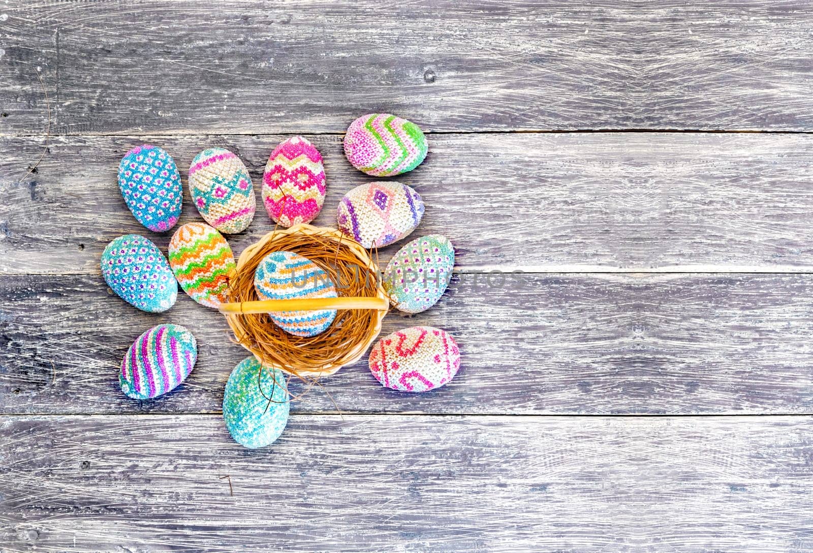 Colorful easter eggs in the nest on wooden basket and wooden table. Happy Easter