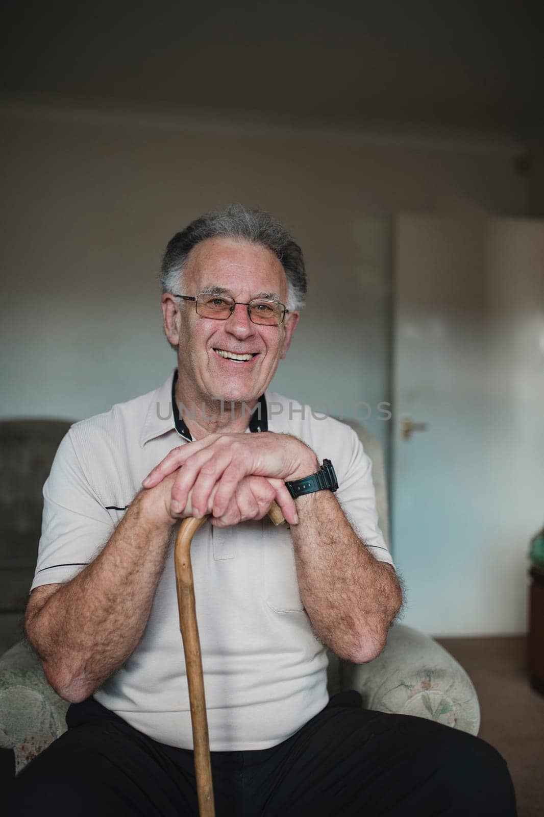 Portrait of a cheerful senior man with his walking stick in the living room of his home.