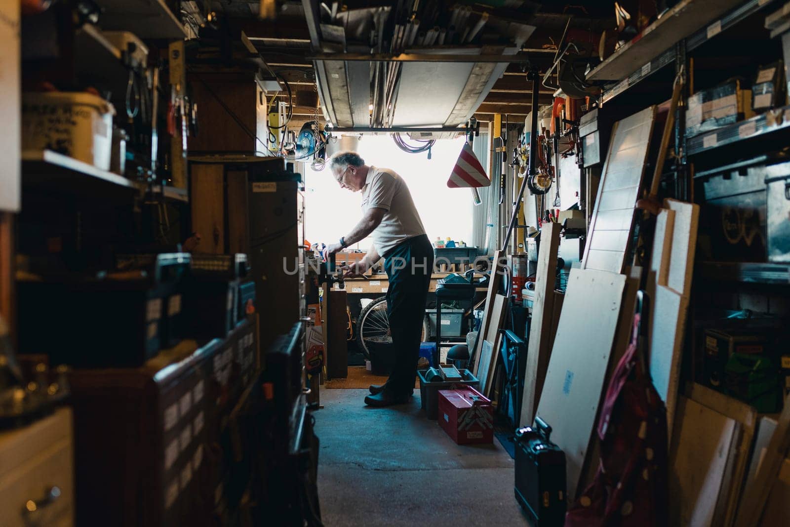 Senior man is working in his shed on a woodwork project. He is fatsening something in to a vice.