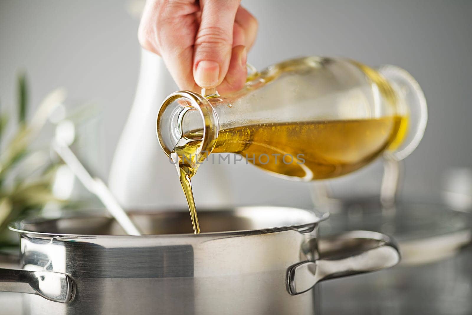 Cooking meal in a pot. Bottle of Extra virgin oil pouring in to pot for cooking meal. Healthy food concept.