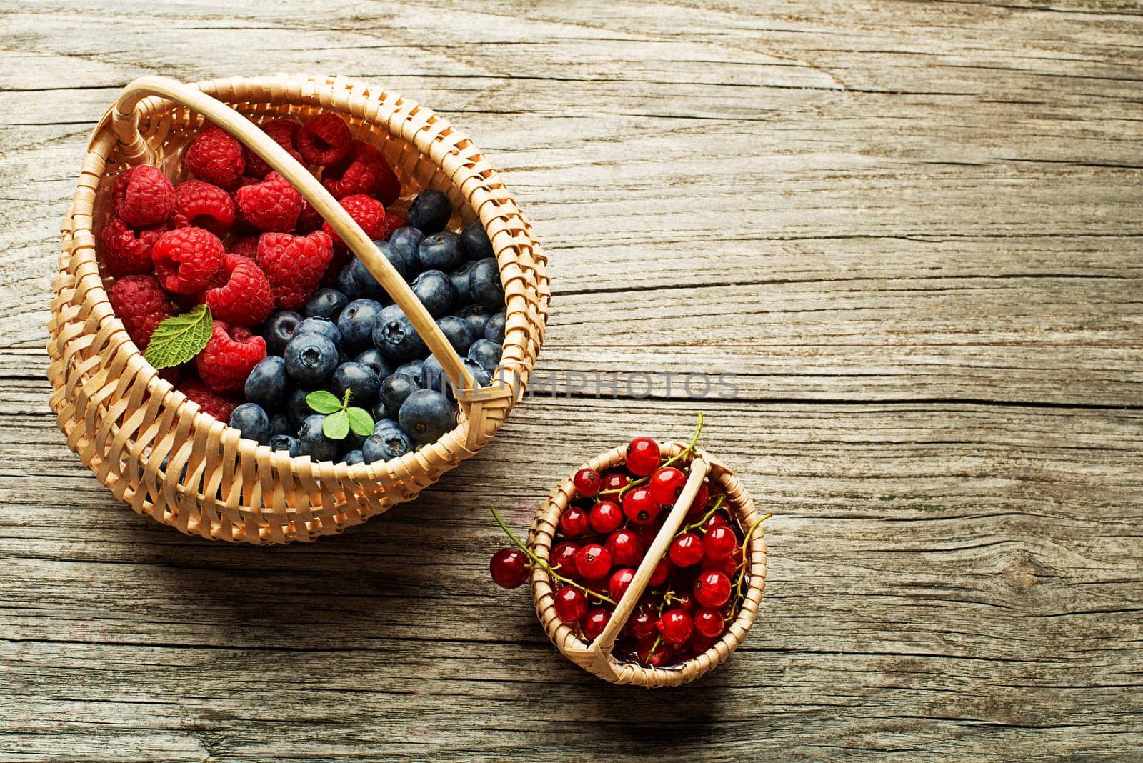 Mix of fresh berries fruit in a basket on wooden background