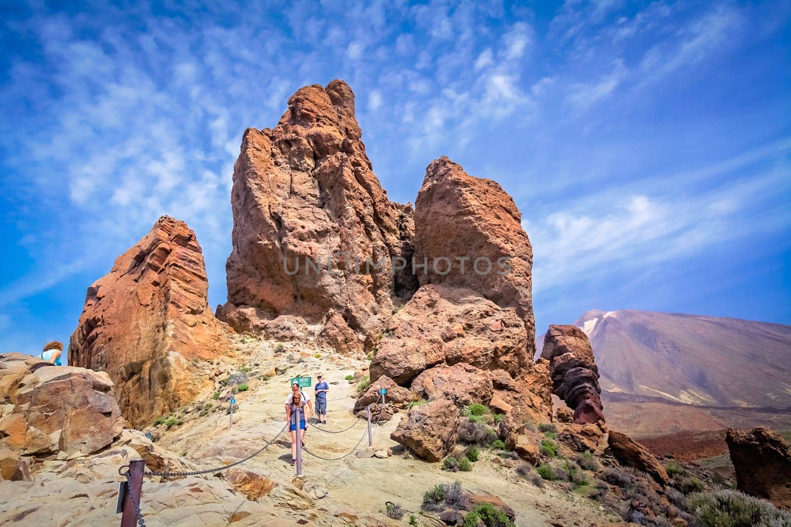 Tenerife, Spain - April 2013 : Tourists on a walking path going to the strangely shaped rock formations with The Teide volcano, spanish highest mountain, in the background, Canary Islands
