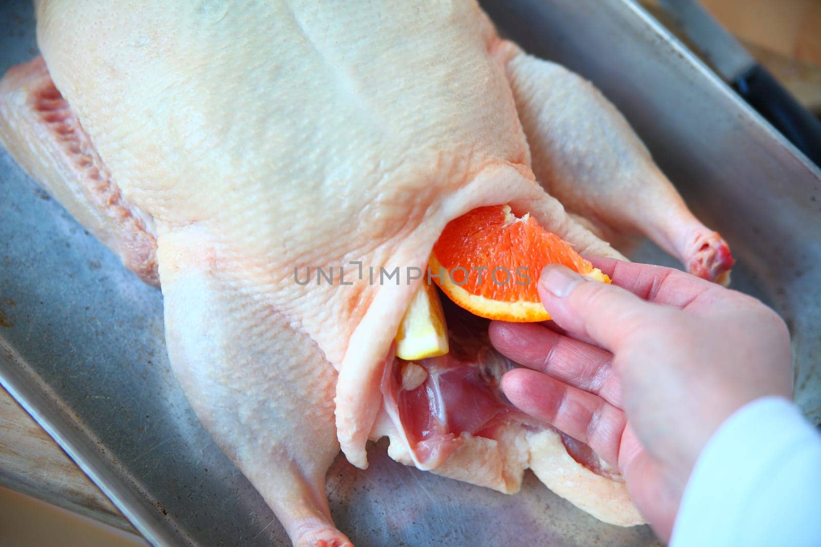 A woman places orange and lemon slices in a duckling cavity