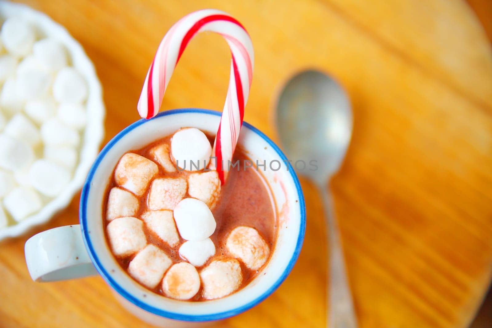 Overhead of cocoa with marshmallows and candy cane